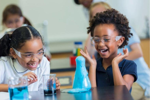 two girls ecstatically experimenting withbubbling blue liquid 